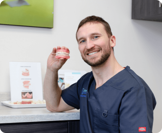 dental hygiene assistant posing with a set of dentures in his hand