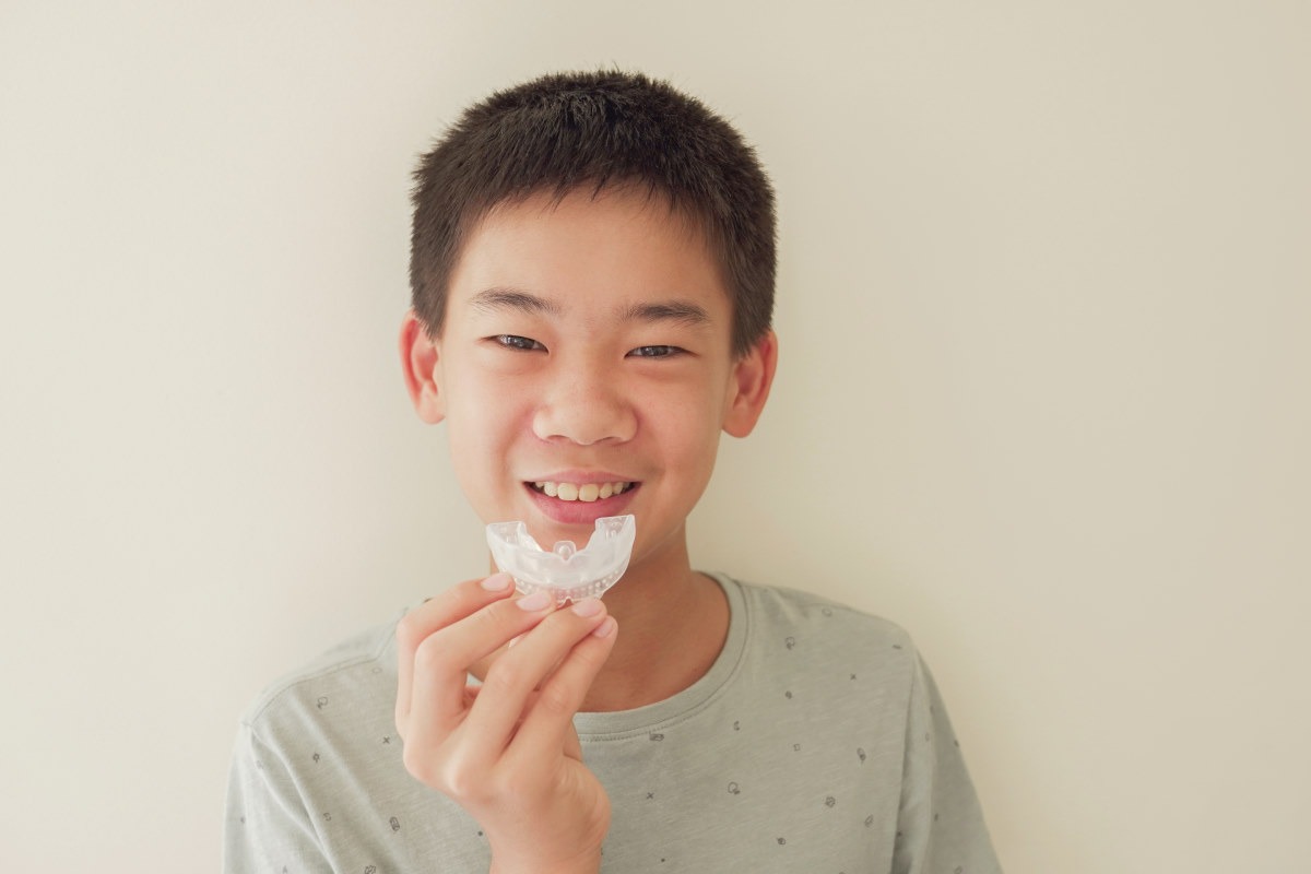 a young asian boy holding a mouth guard