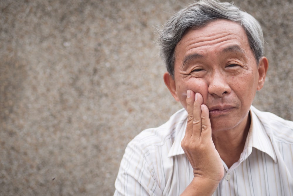 Man Holding His Jaw Due To Denture Problems