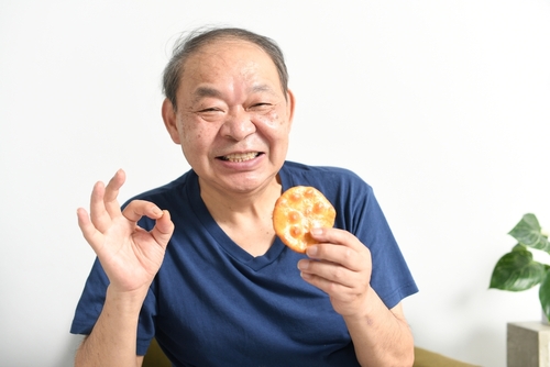 An,Elderly,Man,Holding,A,Rice,Cracker,And,Posing,Ok - Eating after dentures